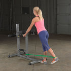 Woman exercising with resistance bands on a weight bench in a home gym setting.