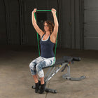 Woman using a resistance band on a weight bench in a home gym setting