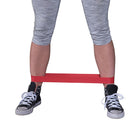 Person using a red resistance band with gray leggings and black sneakers on a white background