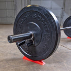 Body-Solid weight plate on a barbell with a red stand against a tiled wall background