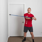 Man using a resistance band against a white door.