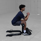 Person using a black exercise device on a gray floor.