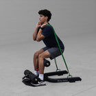 Person using a Body Solid GSS50B Sissy Squat with green resistance band on a gray background