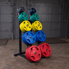 A black metal weight rack holding multiple colorful weight plates in red, blue, yellow, and green, photographed in a garage setting with gray garage doors and concrete floor.
