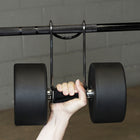 Hand holding a barbell with weights against a brick wall.
