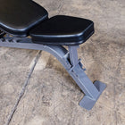 Adjustable weight bench with black padded seat and backrest on a gray metal frame, photographed on a concrete floor.