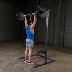 Person lifting a barbell on a squat rack in a gym setting