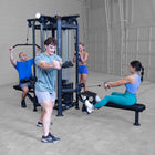 Group of people exercising on a cable machine in a gym.