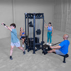 Group of people exercising using a cable machine in a gym setting.