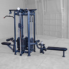 Gym machine with weight plates in a room with gray walls and floor.