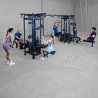 Group of people exercising in a gym with weightlifting equipment.