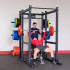Two men using a weightlifting rack in a gym setting.