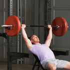 Man performing a bench press with a barbell in a gym setting